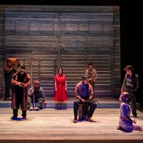 The actors are spread around the stage looking sorrowful.