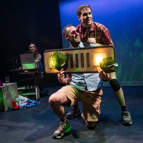 The actors hold a car bumper in front of them. They are positioned behind it as though they are in a car.