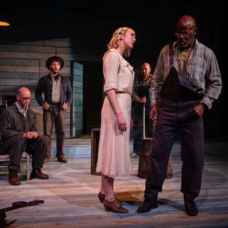 The actors are spread around the stage looking concerned and serious.