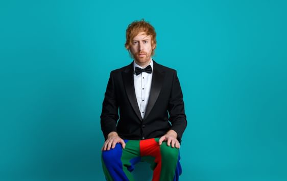 Image of Mark Simmons wearing a suit with clown pants and shoes on