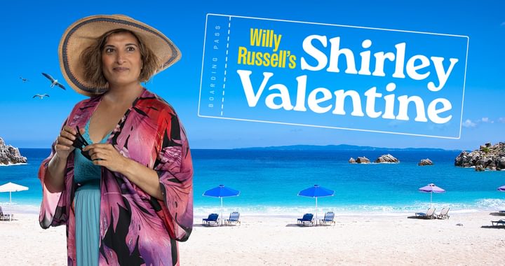 Mina Anwar dressed as Shirley Valentine in front of a beach