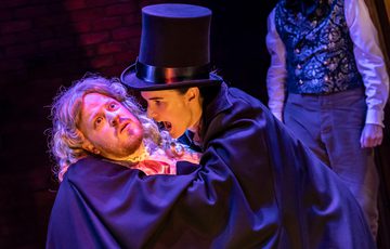 Dracula drinking the blood of an actor with blond wif
