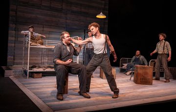 Stefan Race, who plays Curley, is gripping William Young who plays Lennie's ear as the rest of the cast onlook.