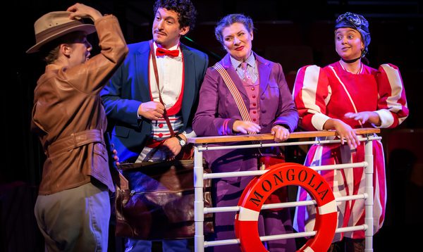 4 people stand behind the guard rail of a boat with a buoyant ring that reads 'Mongolia'