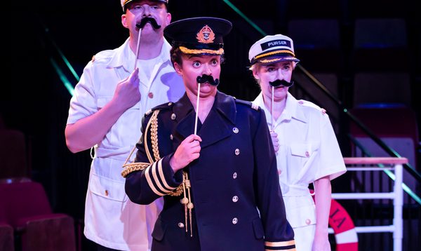 Three people hold big fake black moustaches to their faces as a disguise.