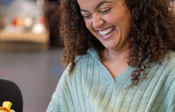 A woman sat down, laughing and looking at a script.