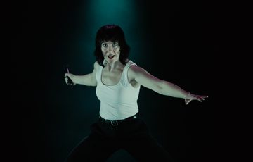 woman in white vest with arms spread wide