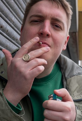 Man lighting a cigarette with Blackpool tower behind him
