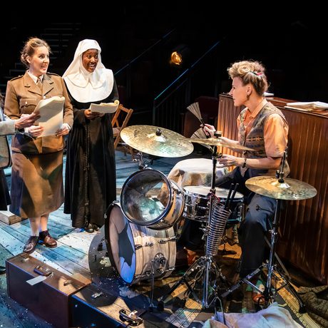 A group of women in 1940s clothes next to a drum kit