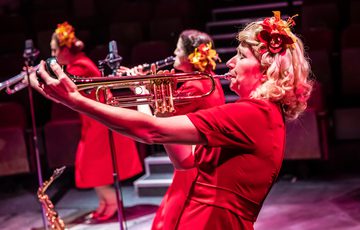 Blonde woman in red dress playing the trumpet