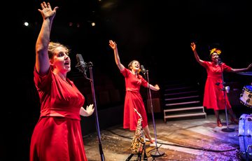 3 women in red dresses singing