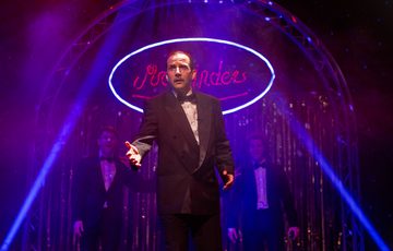 A man in a black suit with purple lighting and haze