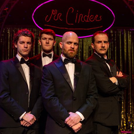 Four men stood together in a black suit, white shirt and a black bow tie