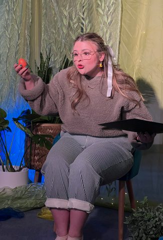 A women with glasses holding a book telling a story