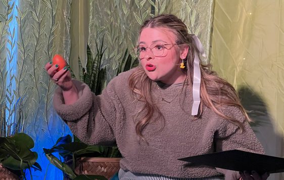 A women with glasses holding a book telling a story