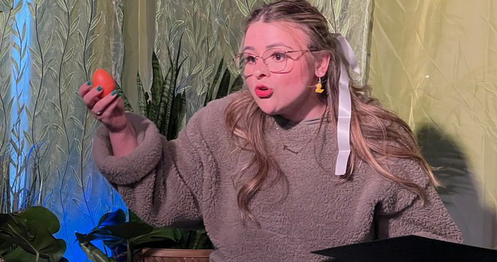 A women with glasses holding a book telling a story