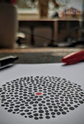 Image of black dots in a circle with a red dot in the middle