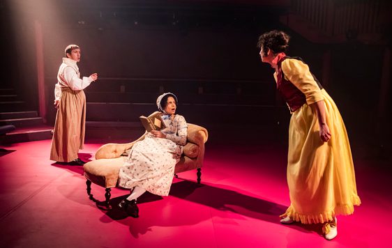 3 actors on stage with one in the middle sitting on a chez lounge