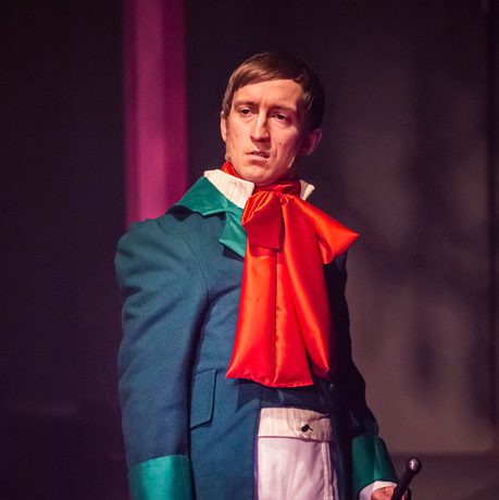 man in regency outfit with large red bow around his neck