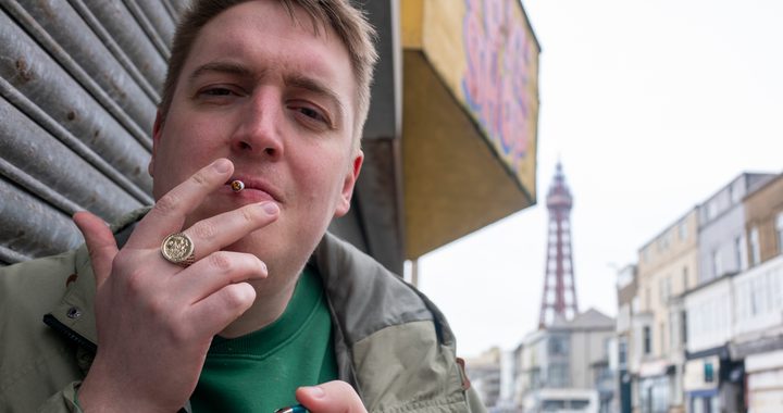 Man lighting a cigarette with Blackpool tower behind him