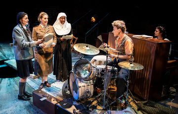 A group of women in 1940s clothes next to a drum kit