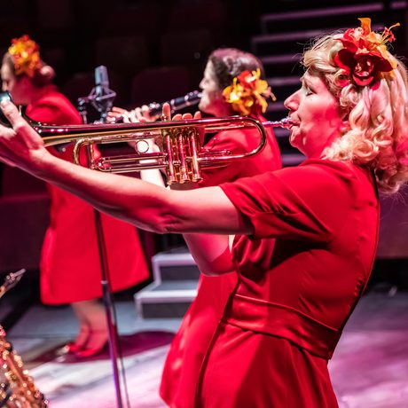 Blonde woman in red dress playing the trumpet