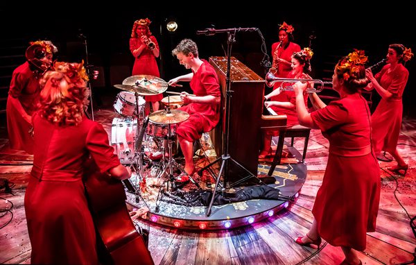 Group of performers in red dresses playing instruments