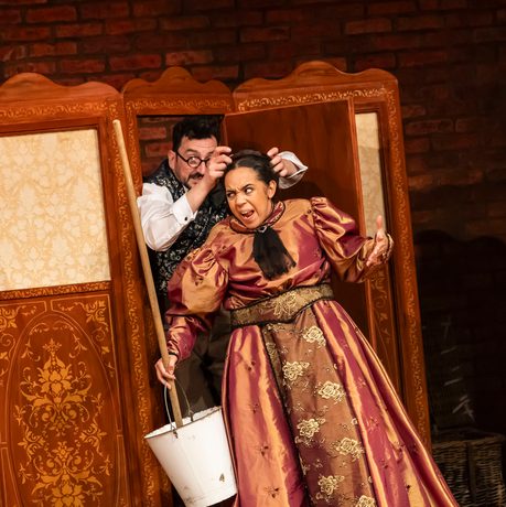 actor putting wig on another actor looking stressed