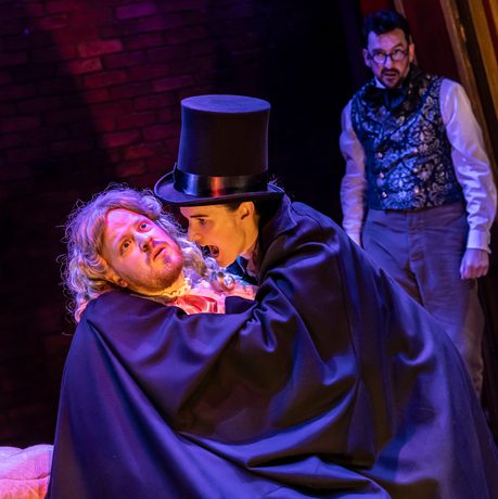 Dracula drinking the blood of an actor with blond wif