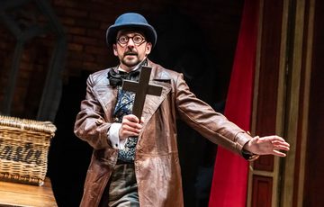 Man in Victorian dress holding a crucifix