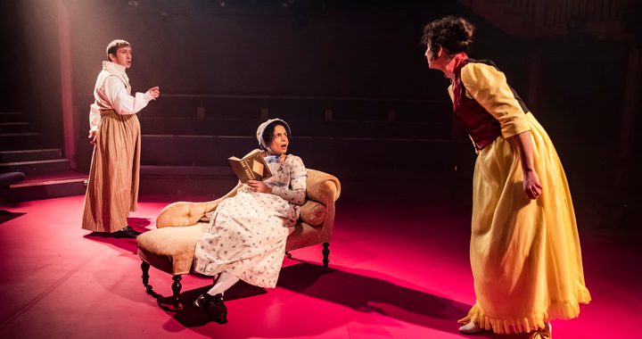 3 actors on stage with one in the middle sitting on a chez lounge