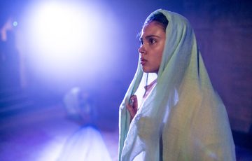 A girl draped in a white scarf sat against a softly blurred background, the atmosphere around her infused with a warm glow.