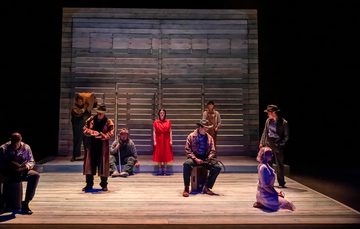 The actors are spread around the stage looking sorrowful.