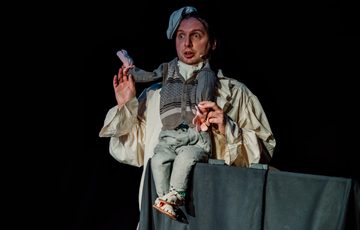 Actor is shown wearing a 'puppet body' model over his head and chest.