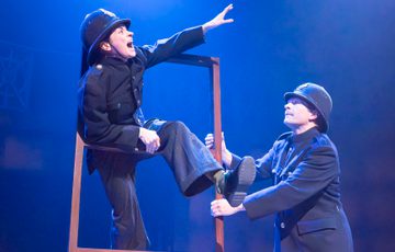 Two actors are shown dressed as police officers