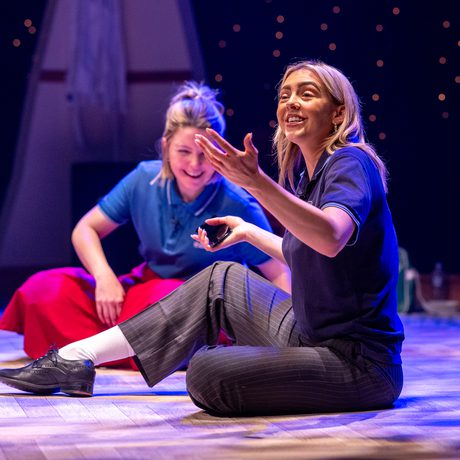 To actresses sit on the stage looking happy