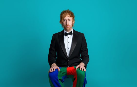 Image of Mark Simmons wearing a suit with clown pants and shoes on