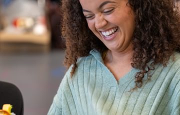 A woman sat down, laughing and looking at a script.