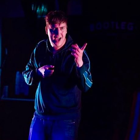 Man on stage in a tracksuit pointing