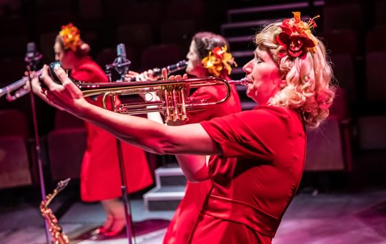 Blonde woman in red dress playing the trumpet