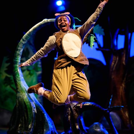 A woman dressed as a mouse jumping in the air