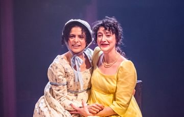 two women sitting next to each other and hugging