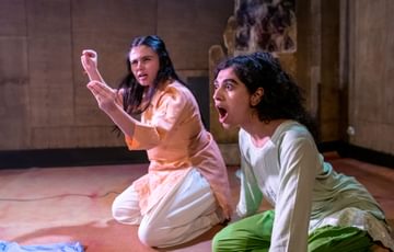 Two girls sat on the floor wearing ethnic clothing